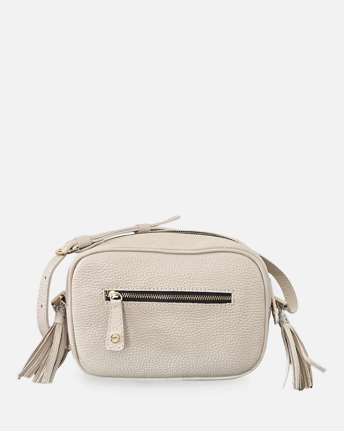 Bolso manos libres color arena con correa de cuero y accesorios de pompones a los lados
